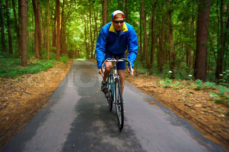 Middle-aged man is riding a road bike along a forest road. Excellent training and healthy exercise, stock photo