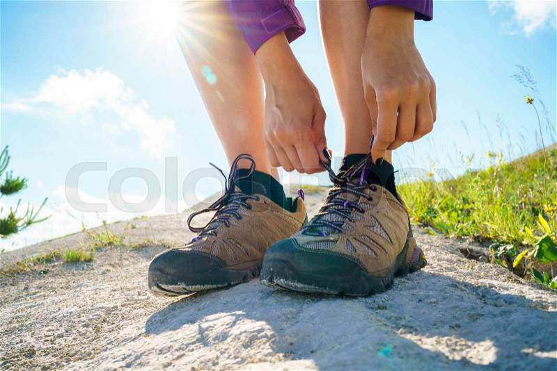 Hiking shoes - woman tying shoe laces. Closeup of female tourist getting ready for hiking, stock photo