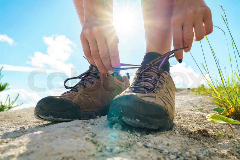 Hiking shoes - woman tying shoe laces. Closeup of female tourist getting ready for hiking, stock photo