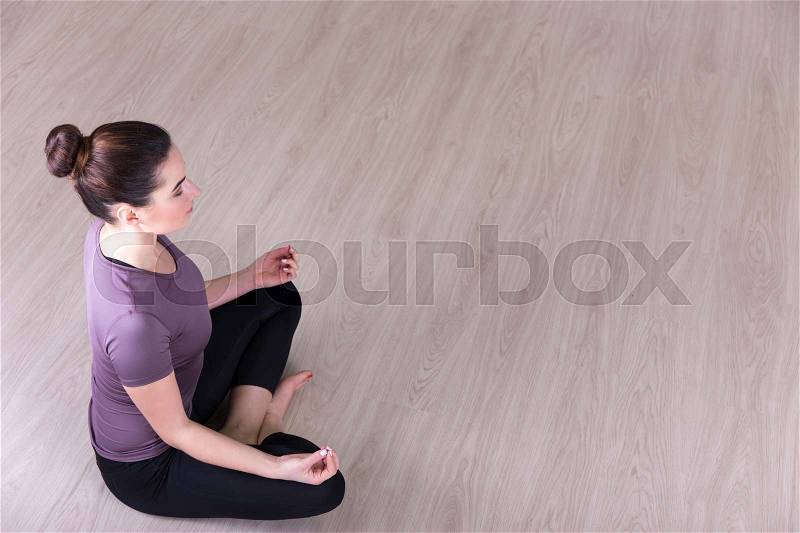 Top view of sporty woman sitting in yoga pose on wooden floor, stock photo