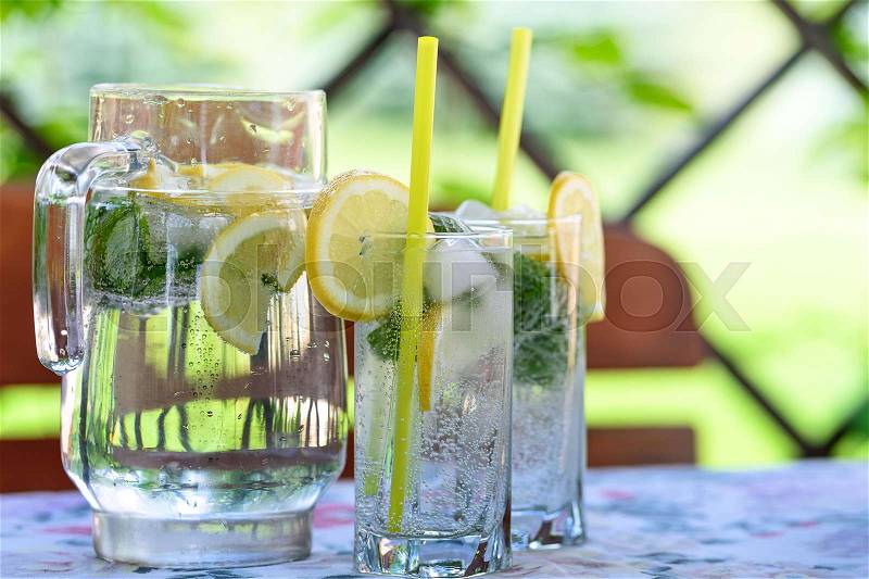 Cool and refreshing drink with lemon, mint and ice in the garden on a hot day, stock photo