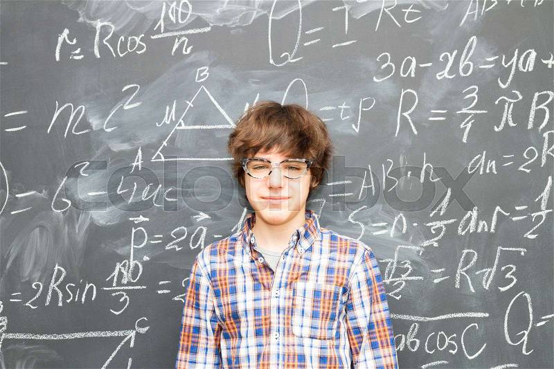 Teenager Boy in glasses, blackboard filled with math formulas background, stock photo