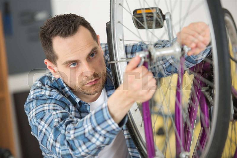 Man is screwing tightly the fork at her bike, stock photo