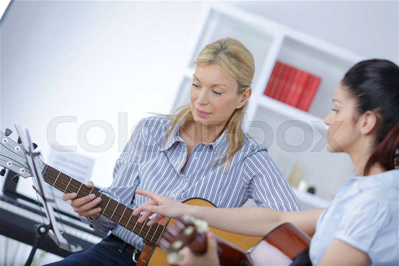 Guitar teacher teaching a girl, stock photo