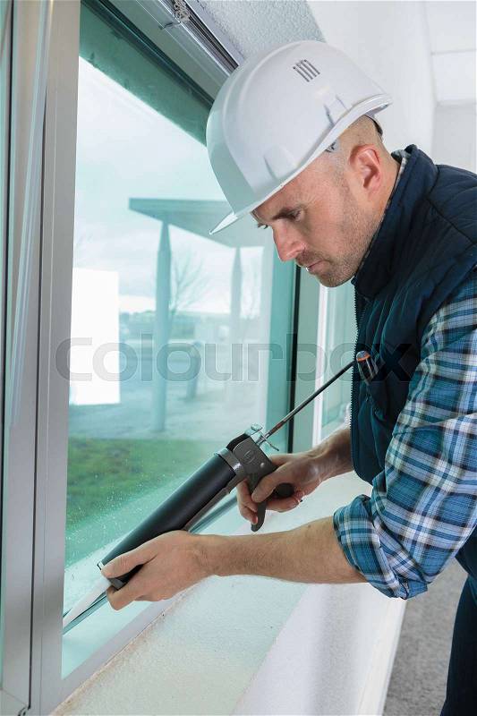 Construction worker installing window in house, stock photo