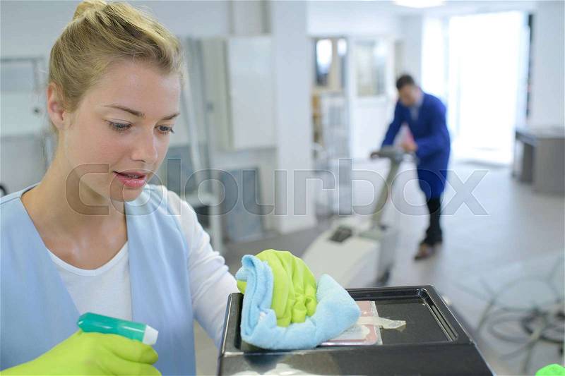 Female cleaner cleaning corridor of business building, stock photo