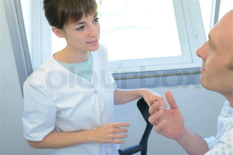 Nurse helping up patient, stock photo