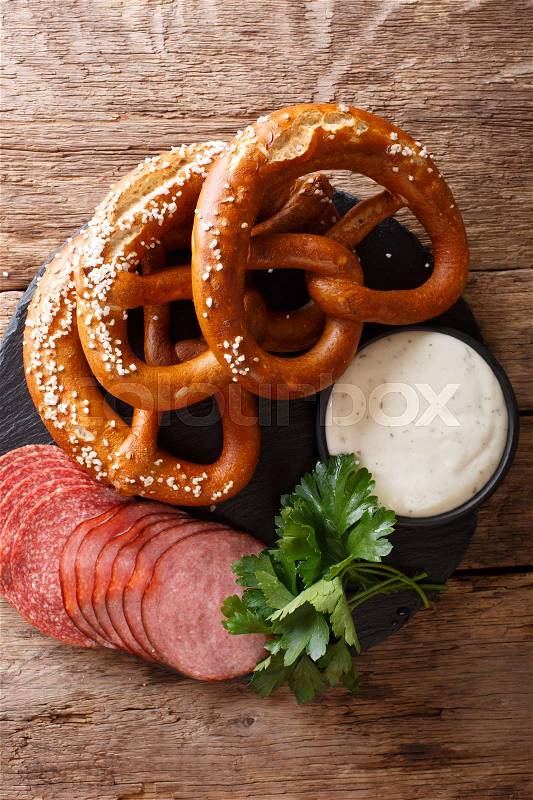 German food: sliced sausages and pretzels with cream sauce close-up on the table. vertical view from above , stock photo