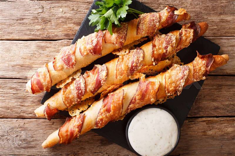 Bread sticks with bacon and cheese close-up and garlic sauce on the table. horizontal view from above , stock photo