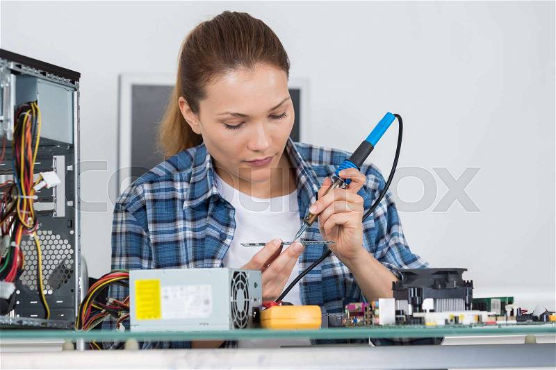 Young female pc technician fixing a computer, stock photo
