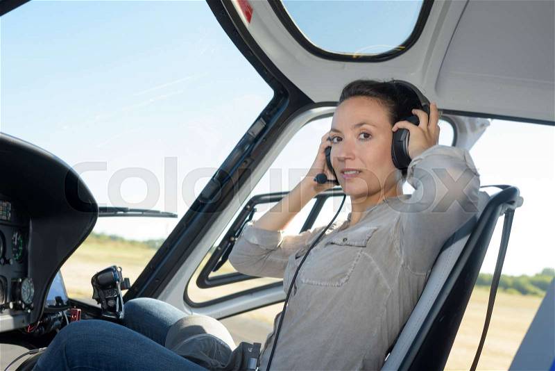 Serious young woman pilot in headset sitting in small plane, stock photo