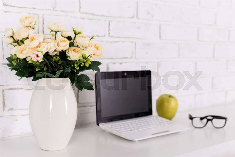 Rose flowers on workplace with modern laptop at home or in office, stock photo
