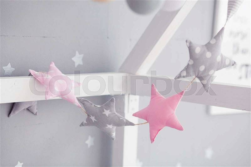 Baby bed with pinwheel garland. Pink and gray stars garland in the children\'s room, stock photo