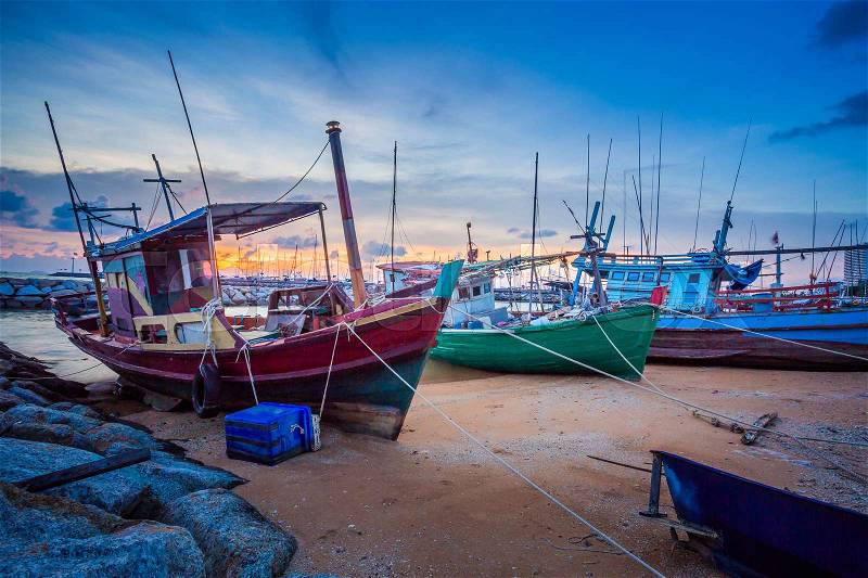 The twilight scene of wooden fishing boat floating at the seashore , Pattaya Thailand, stock photo