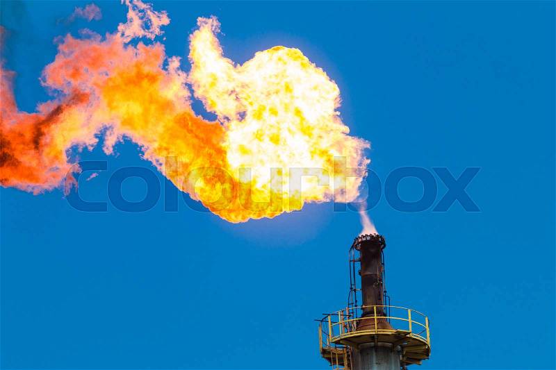 Fire of gas burning from flare structure in oil refinery plant with blue sky, stock photo