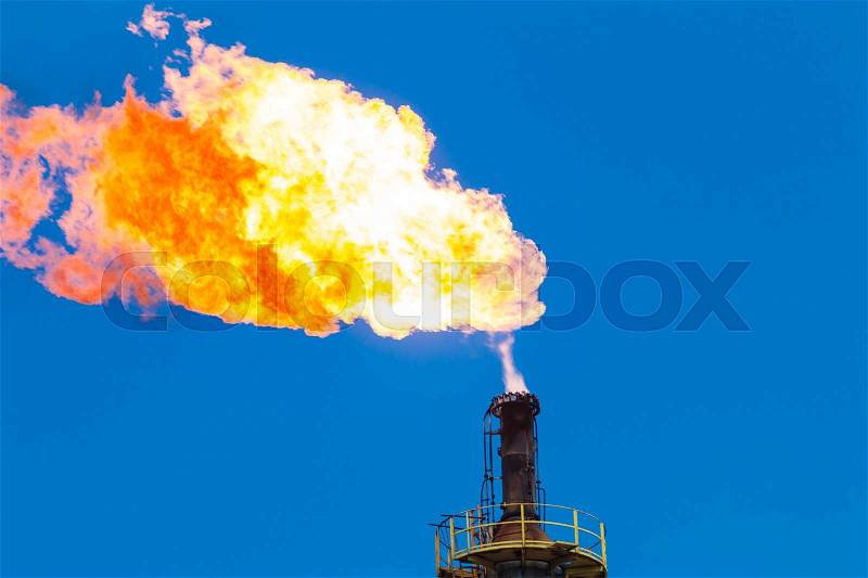 Fire of gas burning from flare structure in oil refinery plant with blue sky, stock photo