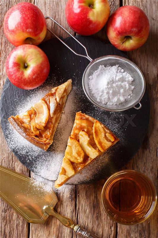 Homemade piece of apple pie with powdered sugar close-up on a table. vertical view from above , stock photo
