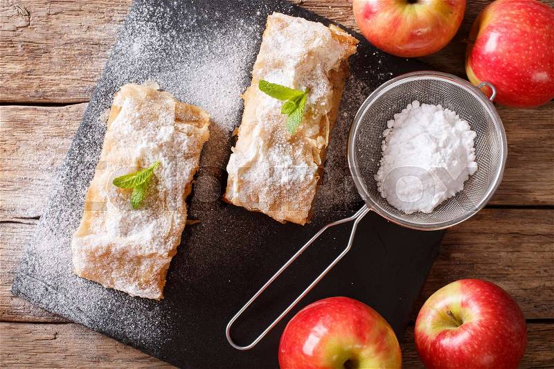 Austrian food: apple strudel with powdered sugar and mint closeup on the table. horizontal view from above , stock photo