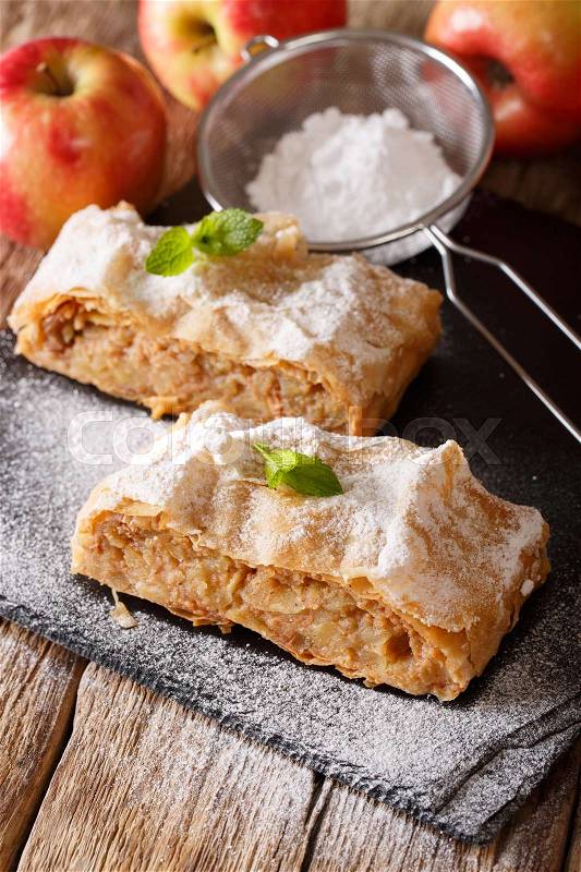 Tasty slice of apple strudel with powdered sugar and mint closeup on a table. Vertical , stock photo