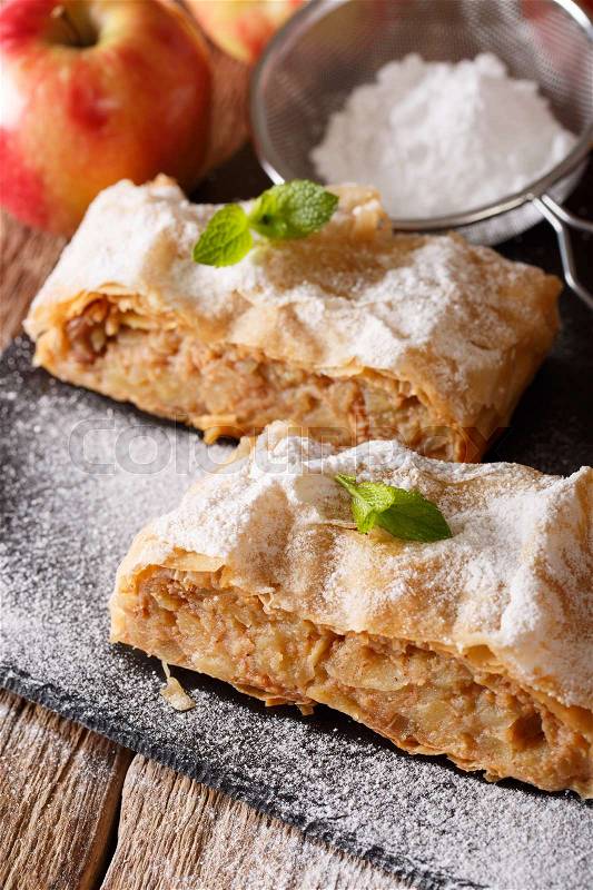 Apple strudel sprinkled with sugar powder close-up on the table. Vertical , stock photo