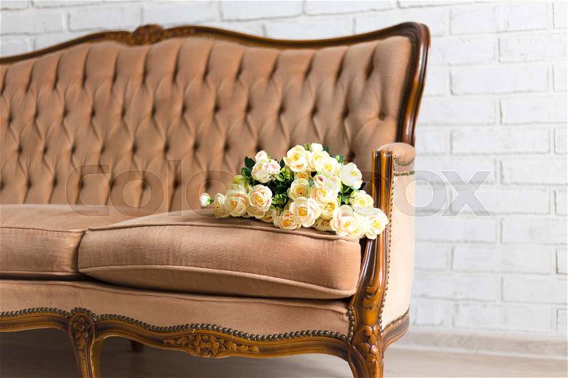 Close up of beautiful rose flowers on vintage sofa, stock photo