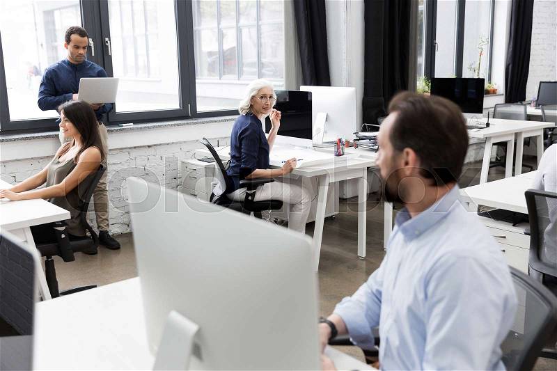 Group of business people talking to each other while working together at the office, stock photo