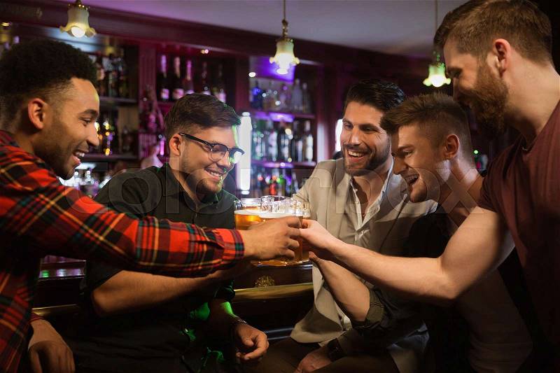 Happy male friends drinking beer and clinking glasses at bar or pub, stock photo