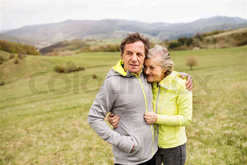 Beautiful active senior runners resting outside in sunny autumn nature, hugging, stock photo