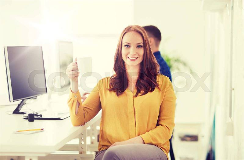 Business, startup, people and break concept - happy businesswoman drinking coffee or tea at office, stock photo