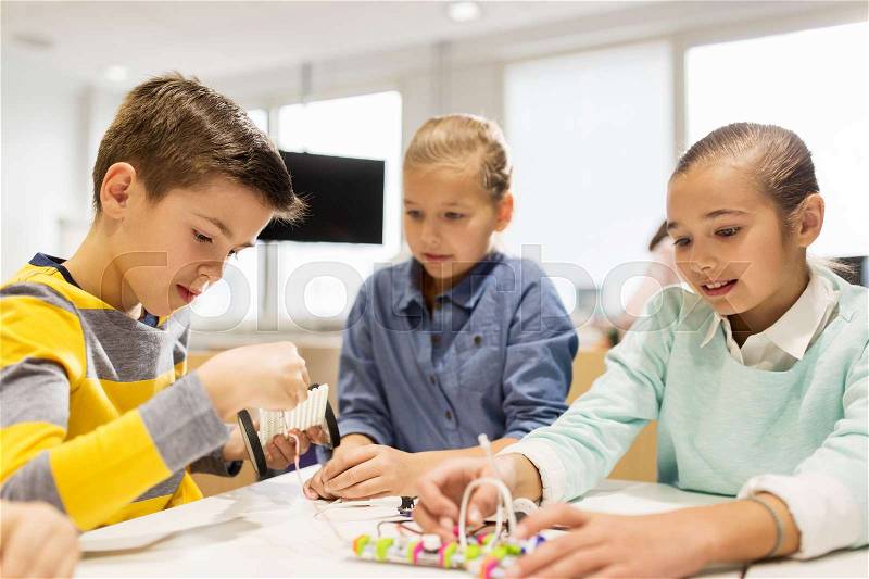 Education, children, technology, science and people concept - group of happy kids building robots at robotics school lesson, stock photo