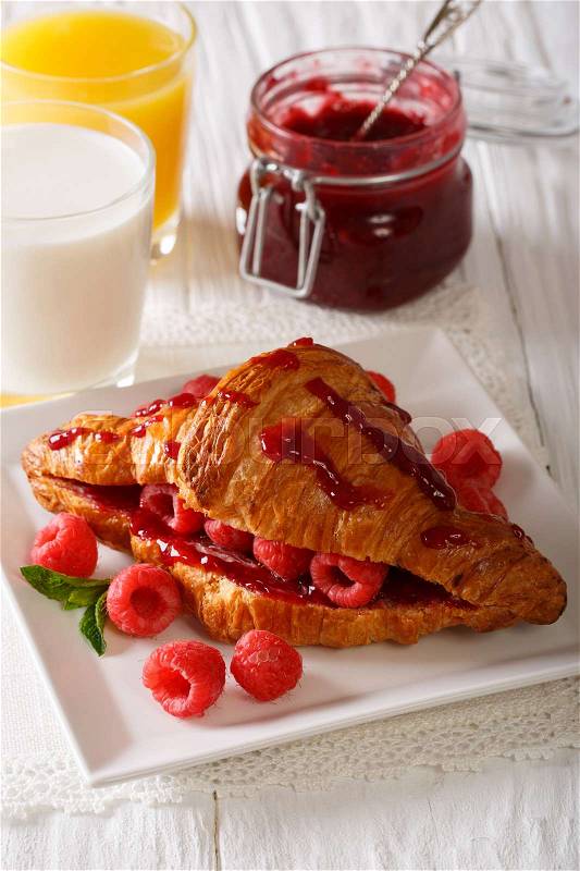 French croissant with raspberry filling, orange juice and milk close-up on the table. vertical , stock photo