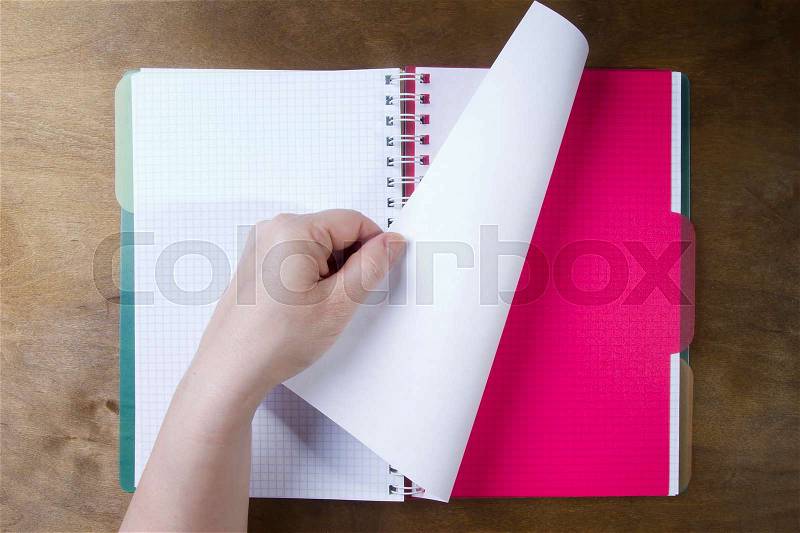Hands flipping page notebooks on a wooden table, stock photo