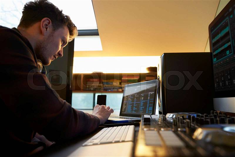 Young Man Composing Music on Laptop Computer in Bedroom, stock photo