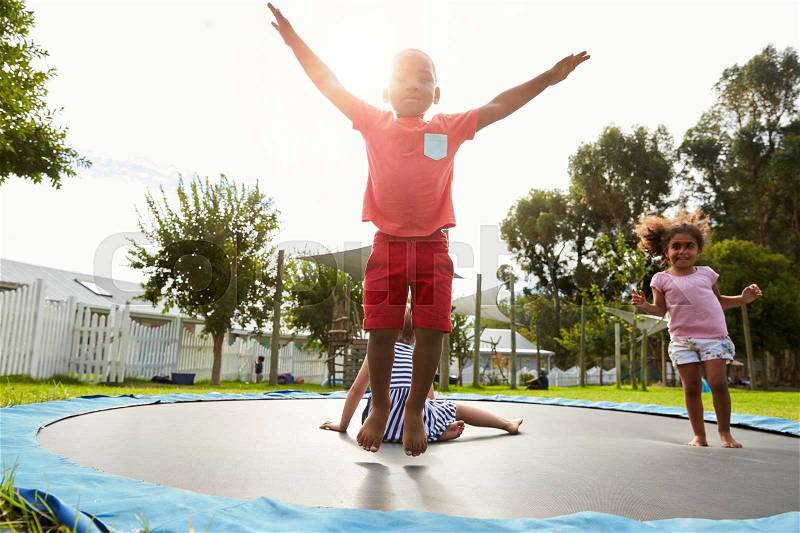 Children At Montessori School Having Fun On Outdoor Trampoline, stock photo
