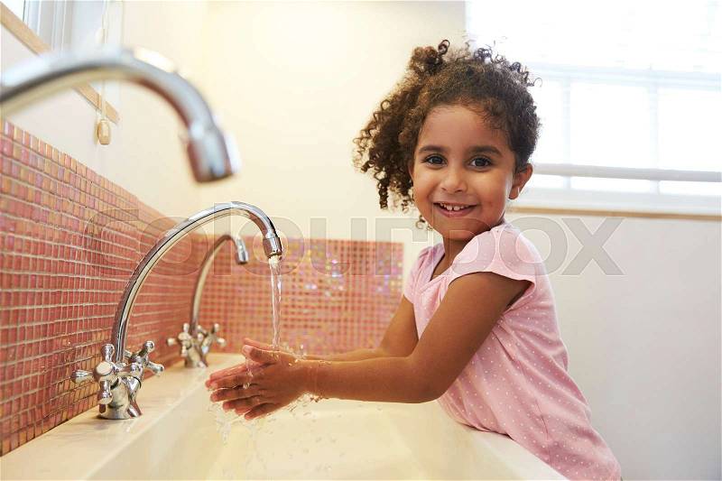 Female Pupil At Montessori School Washing Hands In Washroom, stock photo