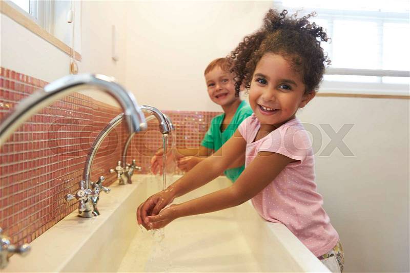 Pupils At Montessori School Washing Hands In Washroom, stock photo