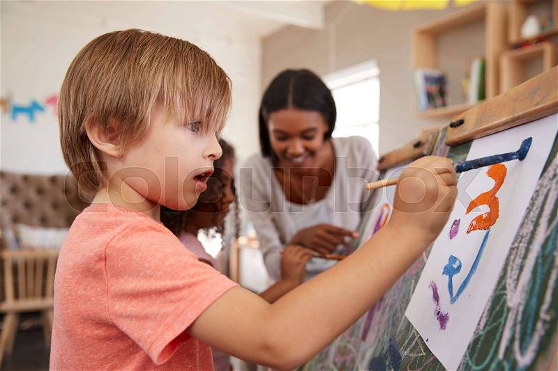 Teacher At Montessori School Helping Children in Art Class, stock photo