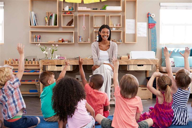 Pupils At Montessori School Raising Hands To Answer Question, stock photo