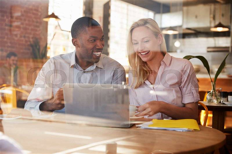 Two Businesspeople Meet In Coffee Shop Shot Through Window, stock photo