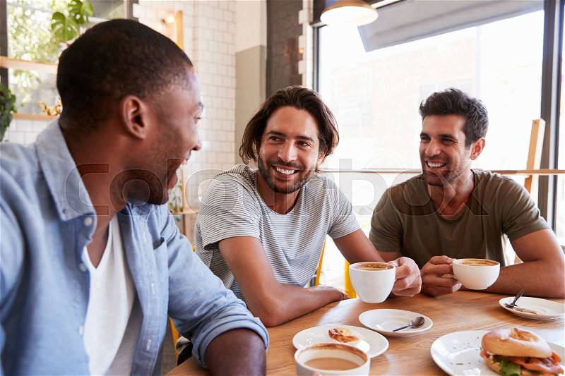 Three Male Friends Meeting For Lunch In Coffee Shop, stock photo