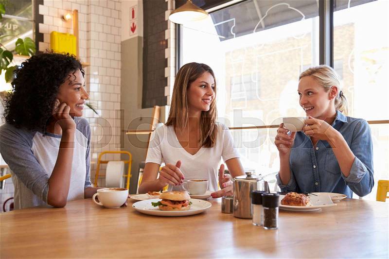 Three Female Friends Meeting For Lunch In Coffee Shop, stock photo
