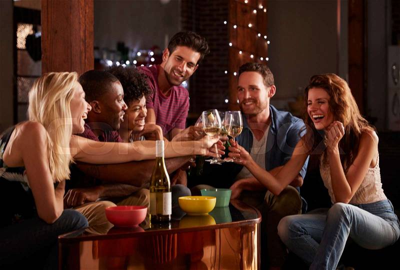 Young adult friends having a party at home making a toast, stock photo