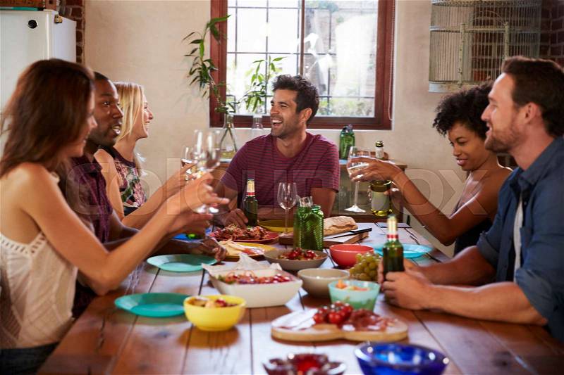 Six young adult friends sitting at table for a dinner party, stock photo