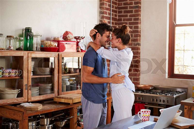 Happy Hispanic couple embracing in kitchen in the morning, stock photo