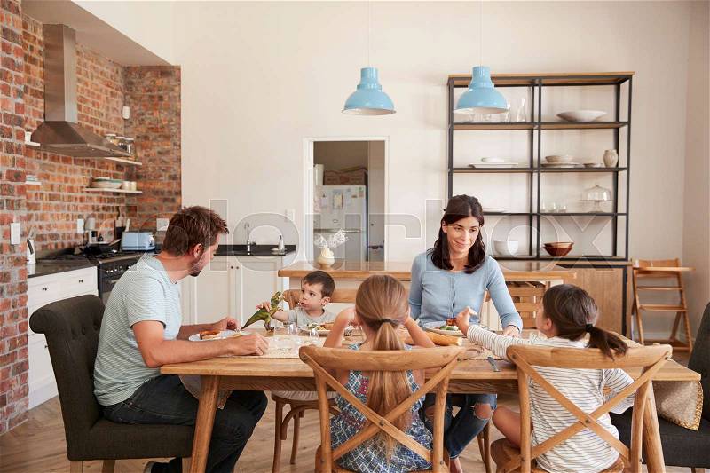 Family Eating Meal In Open Plan Kitchen Together, stock photo