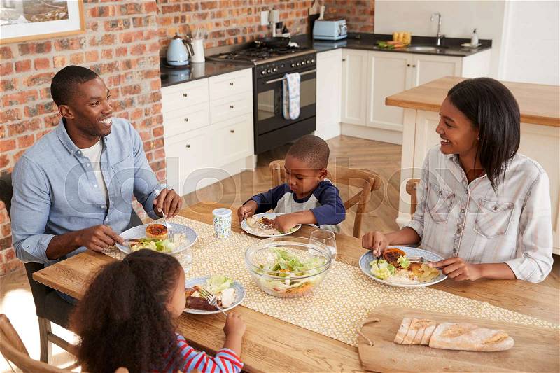 Family Eating Meal In Open Plan Kitchen Together, stock photo