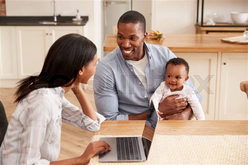 Mother Works From Home As Father Holds Baby Daughter, stock photo