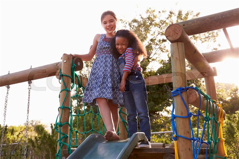 Two Girls Playing Outdoors At Home On Garden Slide, stock photo