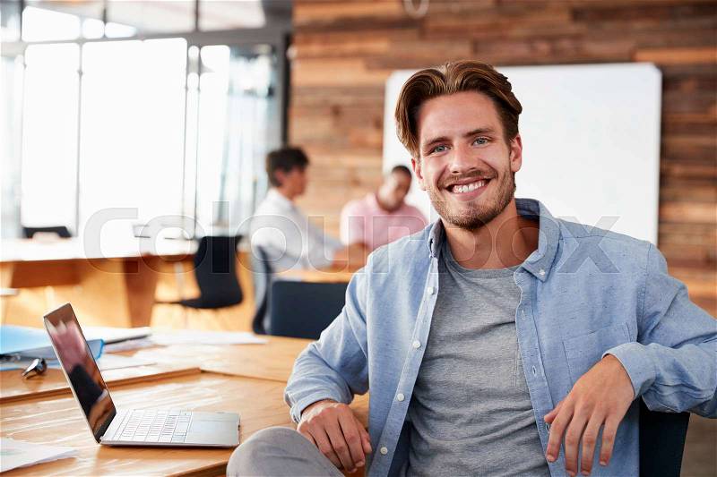 Young casually dressed white man in office looking to camera, stock photo