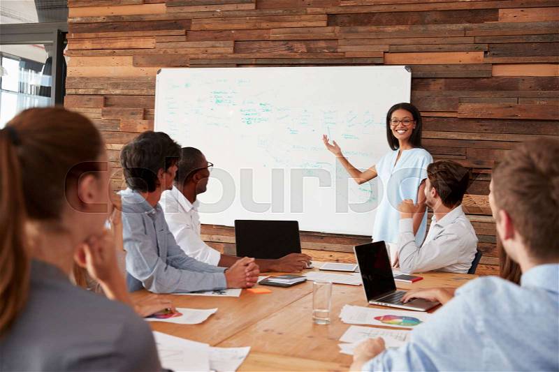 Young black woman giving business presentation at whiteboard, stock photo